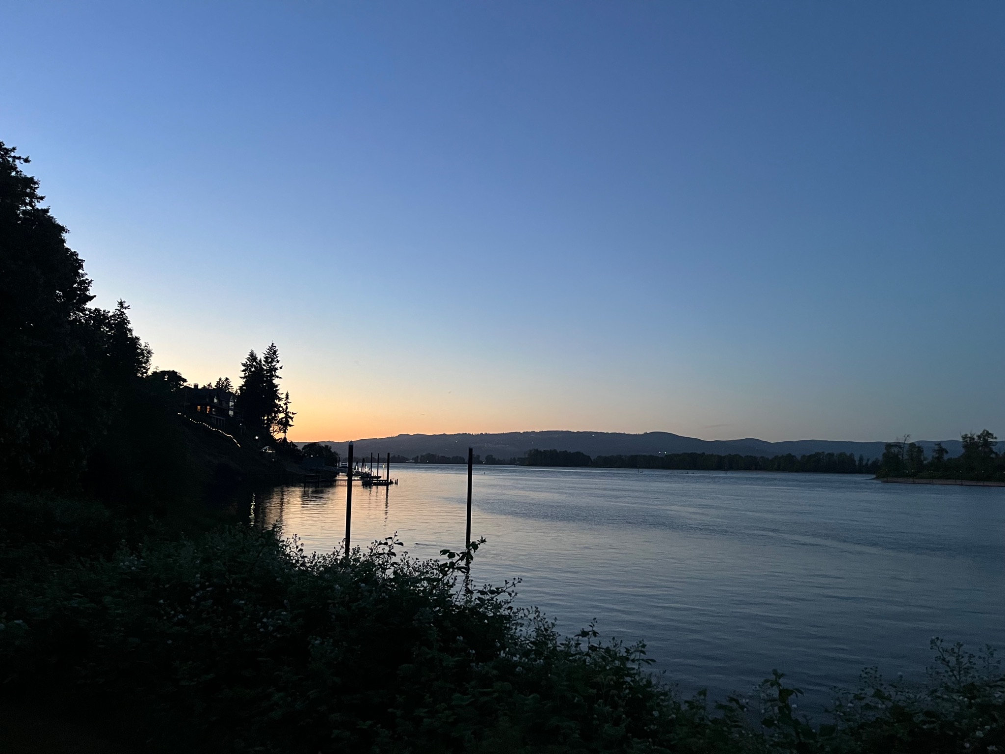 A quiet river at dusk beneath a fading blue sky
