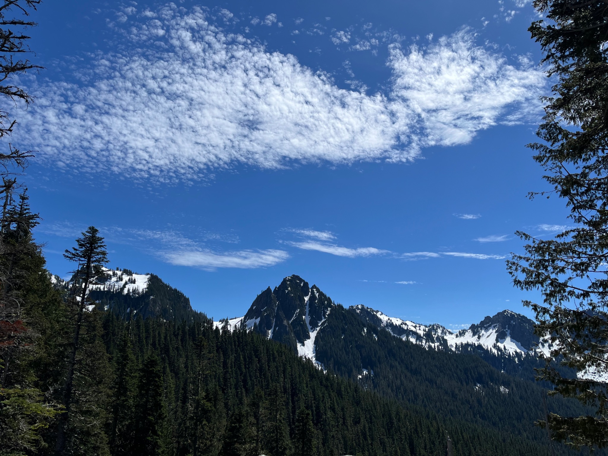 Snowy mountain peaks beneath a sweeping cloud-filled blue sky